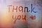 Words thank you and lips are painted in children`s handwriting on wet glass of a window in the light of city lights