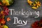 Words Thanksgiving Day written on blackboard with pumpkin and autumn leaves