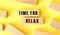 The words TIME FOR RELAX is written on a wooden blocks on a yellow background.