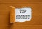The words `top secret` appearing behind torn brown paper. Business concept