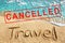 Words TRAVEL on beach sand, blue sea wave landscape, red CANCELLED stamp, Coronavirus pandemic, covid 19 epidemic, cancellation