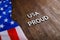 words USA proud laid with silver metal letters on brown wooden surface with flag of United States of America