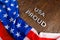 words USA proud laid with silver metal letters on brown wooden surface with flag of United States of America