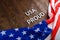 words USA proud laid with silver metal letters on brown wooden surface with flag of United States of America