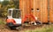 Work on the construction site of an ecological house. The excavator adjusts the terrain. A small digger in the garden.