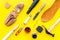 Work desk of shoemaker with instruments, wooden shoe and leather. Yellow background top view