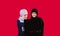 Work online. Concentrated Muslim female friends are working on a laptop on a red background with blank space.