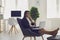 Work online at home. A young business woman sits comfortably working with a laptop in an armchair in an office room at