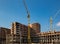 Work in progress on a new apartment block. Tall building under construction with cranes. Construction Site of New Building