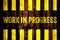 Work in progress warning sign with yellow and black stripes painted over cement concrete wall coarse surface texture background.