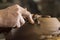 Work with red clay. Male hands form a bowl on a spinning pottery wheel.