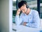 Work satisfaction is a terrible thing to waste. a young man looking stressed out while using a headset and computer in a