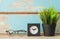 Work space decorative with glasses,clock and green grass pot over grunge blue wooden background