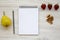 Work space for healthy person: blank notepad, pencil, walnuts, strawberries and pear on a white wooden background.