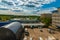 Work yard, cars, hangar, office windows, pond, forest, high-rise buildings in the distance.