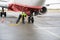 Worker Adjusting Chock By Airplane Wheels While Charging It