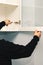 Worker adjusts the loop on the kitchen cabinet with a screwdriver. Installation of kitchen.