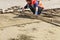 Worker aligns the sand base with a wooden board for laying paving slabs on the sidewalk