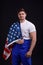 A worker with an American flag on his shoulder looks directly against a black background. Front view