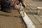 Worker applies white paint markings on the curb. profession urban service