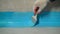 A worker is applying waterproofing paint to the floor in the bathroom. The process of applying waterproofing in the