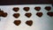 Worker arranging heart shaped dark chocolate on tray