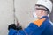 Worker in blue protective clothing, mask and hard hat , working on dismantling concrete walls , drill, close- up