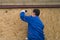 A worker in a blue uniform drills wooden boards in the lower part of the house