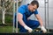 Worker in blue uniform, on the street, checks the wooden Foundation for the greenhouse, with a special