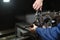 A worker in blue workwear installs a new drill for machining a metal part on a CNC machine tool. Hands of a worker close