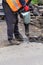 A worker breaks up old asphalt with an electric jackhammer