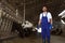 Worker with bucket in cowshed on farm. Animal husbandry