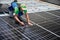 Worker building photovoltaic solar panel system on rooftop of house with help of wrench.