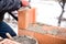 Worker buliding brick walls at house construction site, bricklayer