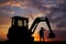 Worker and bulldozer at sunset