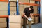 Worker With Cardboard Boxes Writing On Clipboard