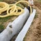 A worker carries a yellow perforated drainage pipe. Groundwater drainage works in the field