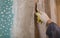 Worker is cementing by the putty knife the wall in room that is under construction, remodeling, renovation, extension