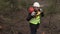 Worker with chainsaw on shoulder talking on phone on steep forest slope