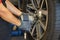 Worker changing wheel with electric wrench in the auto service garage