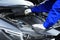 Worker checking motor oil level in car with dipstick, closeup