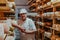 A worker at a cheese factory sorting freshly processed cheese on drying shelves