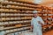 A worker at a cheese factory sorting freshly processed cheese on drying shelves