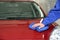 Worker cleaning automobile bonnet with rag at car wash