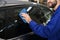 Worker cleaning automobile window with rag at car wash