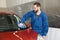 Worker cleaning automobile windshield with rag