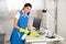 Worker Cleaning Computer Desk With Spray And Sponge