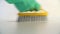Worker cleaning floor with detergent using yellow brush and green protective gloves