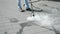 worker cleaning street with hot steamcloseup, special device and long metal hose, modern technology,