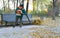 Worker is cleaning up fallen leaves with backpack blower